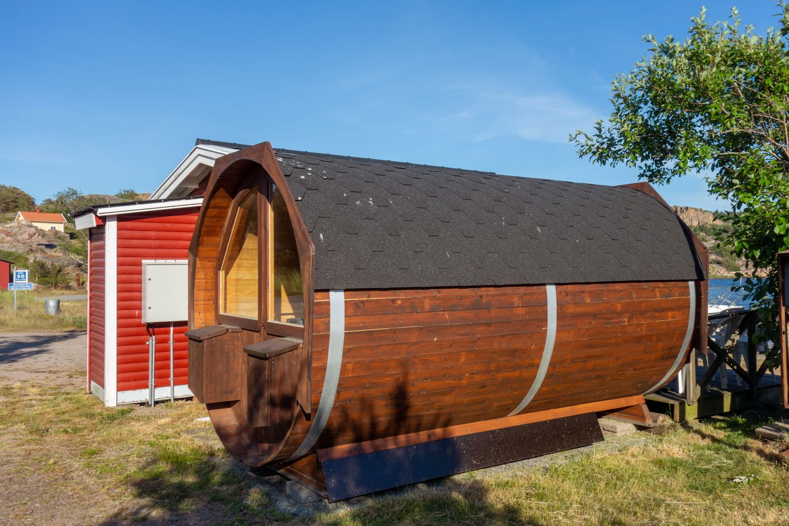 A cedar barrel sauna on a deck beside a lake